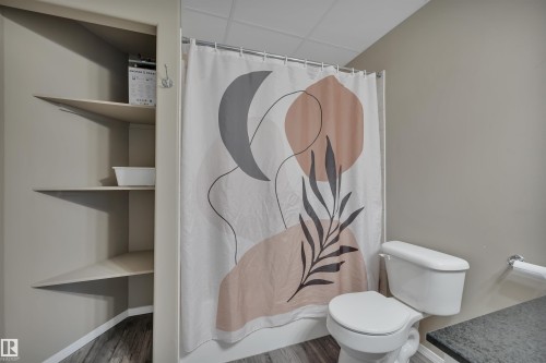 Bathroom featuring a shower with a decorative curtain, a toilet, and built-in shelving - 5 Parkview Crescent, Calmar, AB - Indoor Photo Showing Bathroom