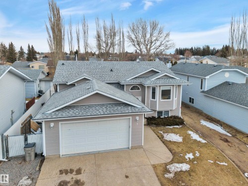 This property features a light-colored siding exterior, a multi-gabled roof, and an attached garage with a white door - 5 Parkview Crescent, Calmar, AB - Outdoor