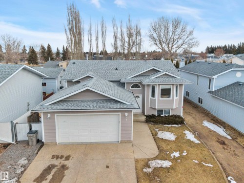 This property features a light-colored exterior with a grey roof and an attached garage - 5 Parkview Crescent, Calmar, AB - Outdoor