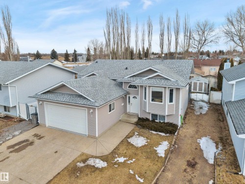 This property features a light-colored exterior with a grey shingle roof and an attached garage with a white door - 5 Parkview Crescent, Calmar, AB - Outdoor