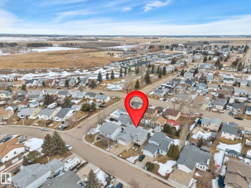 Aerial view of the property and surrounding neighborhood, featuring residential homes, roads, and open fields in the background - 5 Parkview Crescent, Calmar, AB - Outdoor With View