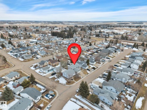 Aerial view showcasing the property within a residential neighborhood featuring homes with grey roofs and surrounding open fields - 5 Parkview Crescent, Calmar, AB - Outdoor With View
