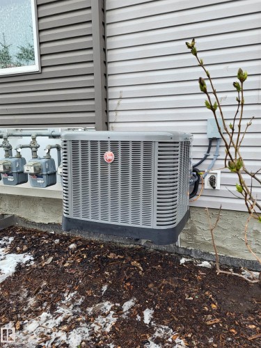 The property features an air conditioning unit and gas meters, set against a backdrop of horizontal siding - 32 2121 Haddow Drive, Edmonton, AB - Outdoor