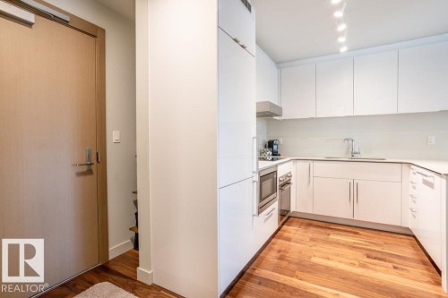 The kitchen features white cabinetry, integrated stainless steel appliances, and track lighting - 2506 10360 102 Street, Edmonton, AB - Indoor Photo Showing Kitchen