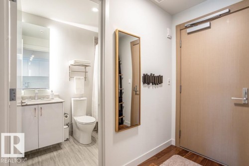 The property features a bathroom with a white vanity and toilet, and wood-look flooring in the entryway - 2506 10360 102 Street, Edmonton, AB - Indoor Photo Showing Bathroom