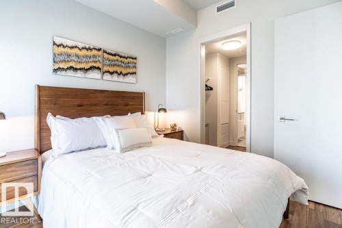 The property features a bedroom with a wooden headboard, light walls, and wood-style flooring - 2506 10360 102 Street, Edmonton, AB - Indoor Photo Showing Bedroom