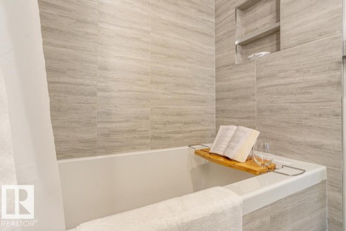 Bathroom featuring a bathtub and tiled walls, with a built-in shower niche - 2506 10360 102 Street, Edmonton, AB - Indoor Photo Showing Bathroom