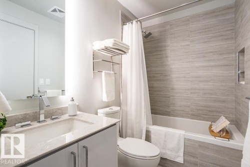 The bathroom features a vanity with a rectangular sink and a polished chrome faucet, a shower/tub combination with light grey tiled walls, and a built-in shower niche - 2506 10360 102 Street, Edmonton, AB - Indoor Photo Showing Bathroom