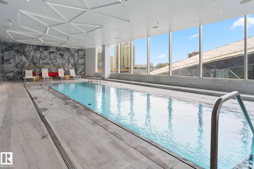 Indoor swimming pool featuring floor-to-ceiling windows, a textured accent wall, and a unique geometric ceiling design - 2506 10360 102 Street, Edmonton, AB - Indoor Photo Showing Other Room With In Ground Pool