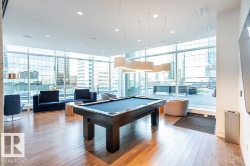 This recreational area features hardwood flooring, a billiards table, and large windows offering extensive views - 2506 10360 102 Street, Edmonton, AB - Indoor Photo Showing Other Room