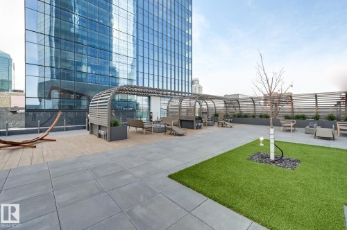 Rooftop terrace featuring a patterned paved surface, a green turf area with a tree, and lounge seating - 2506 10360 102 Street, Edmonton, AB - Outdoor