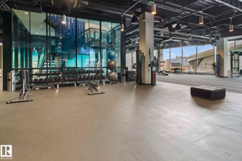 Fitness area featuring a rubberized floor, a wide selection of free weights, and large windows providing natural light - 2506 10360 102 Street, Edmonton, AB - Indoor Photo Showing Gym Room