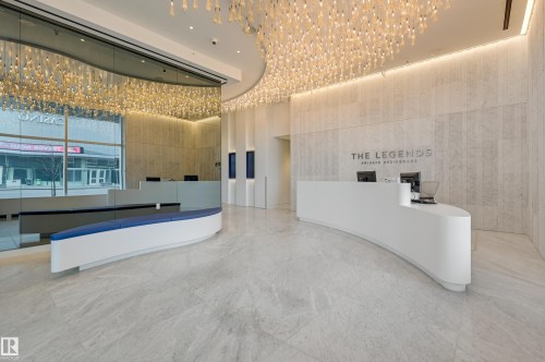 Welcoming lobby area featuring a grand chandelier, curved reception desk, and a seating bench - 2506 10360 102 Street, Edmonton, AB - Indoor Photo Showing Other Room