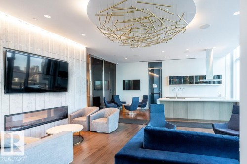 This inviting common area features hardwood flooring, a modern fireplace, and a large television - 2506 10360 102 Street, Edmonton, AB - Indoor With Fireplace