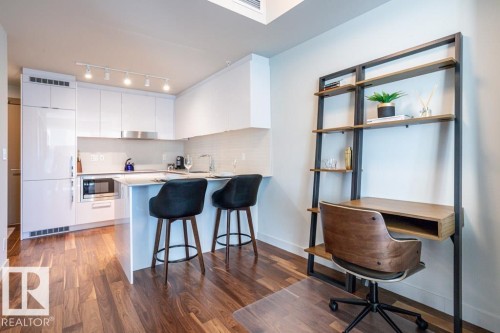 The property features a kitchen with white cabinetry, a white tile backsplash, and stainless steel appliances, including a microwave - 2506 10360 102 Street, Edmonton, AB - Indoor Photo Showing Kitchen