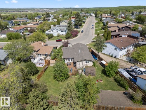 Rear exterior featuring a multi-level deck, lower patio area, and expansive sloped lawn with mature trees - 4003 50A Avenue, Cold Lake, AB - Outdoor With View