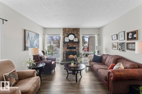 The living area features a stone fireplace, light-colored walls, and large windows providing natural light - 4003 50A Avenue, Cold Lake, AB - Indoor Photo Showing Living Room With Fireplace