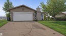 The property features a two-car garage, a concrete driveway, and a well-maintained lawn with mature trees - 4003 50A Avenue, Cold Lake, AB  - Outdoor 