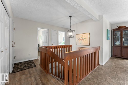 The property offers a landing area with a wooden staircase and railing, illuminated by a hanging light fixture - 4003 50A Avenue, Cold Lake, AB - Indoor Photo Showing Other Room