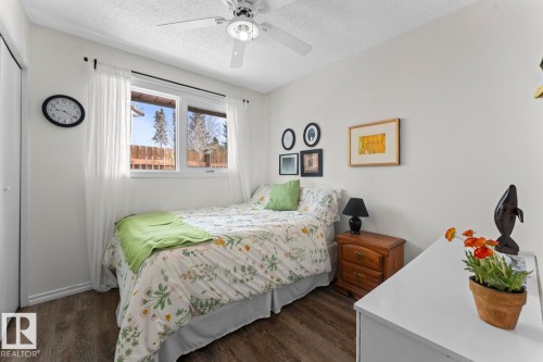 This room features a ceiling fan, a window with white sheer curtains, and wood-look flooring - 4003 50A Avenue, Cold Lake, AB - Indoor Photo Showing Bedroom