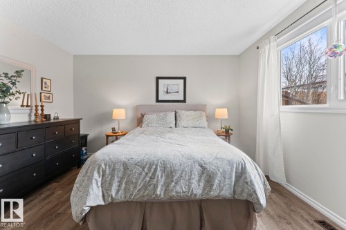 This bedroom features light-toned walls, hardwood style flooring, and a large window with white trim providing natural light - 4003 50A Avenue, Cold Lake, AB - Indoor Photo Showing Bedroom