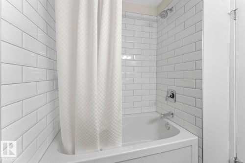 Bathroom with a white subway tile surround, a shower head with an adjustable spray pattern, and a bathtub with chrome fixtures - 4003 50A Avenue, Cold Lake, AB - Indoor Photo Showing Bathroom