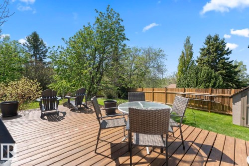 Expansive wood-decked patio featuring a solid wood privacy fence, mature trees, a manicured lawn, and a storage shed - 4003 50A Avenue, Cold Lake, AB - Outdoor With Deck Patio Veranda