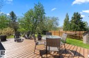 Expansive wood-decked patio featuring a solid wood privacy fence, mature trees, a manicured lawn, and a storage shed - 4003 50A Avenue, Cold Lake, AB  - Outdoor With Deck Patio Veranda 