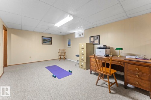The property features a versatile room with carpeted flooring, light-colored paneled walls, and a drop ceiling with fluorescent lighting - 4003 50A Avenue, Cold Lake, AB - Indoor