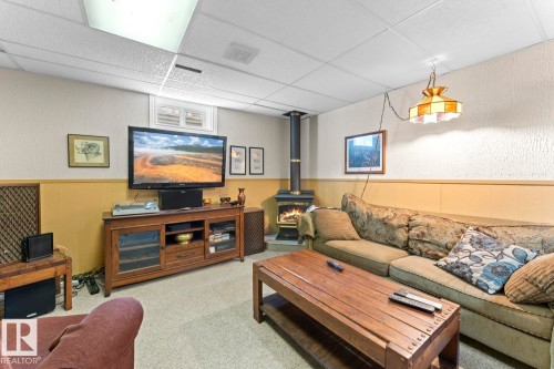 The living area features a wood-burning stove, carpeting, and a drop ceiling with recessed lighting - 4003 50A Avenue, Cold Lake, AB - Indoor Photo Showing Other Room