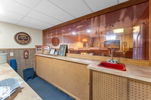 The property features a built-in bar area with a red sink and faucet, a spacious countertop, and pegboard paneling - 4003 50A Avenue, Cold Lake, AB - Indoor