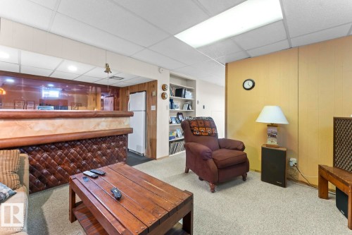Recreational space featuring a built-in bar with tufted paneling, carpeted flooring, and a drop ceiling with recessed lighting - 4003 50A Avenue, Cold Lake, AB - Indoor