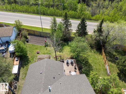 Expansive backyard featuring a wood deck, manicured lawn, and mature trees - 4003 50A Avenue, Cold Lake, AB - Outdoor With View