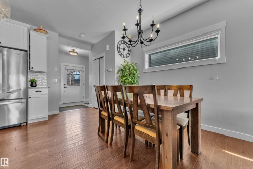 Open concept living area featuring hardwood flooring, a modern chandelier, and a horizontal window - 6406 169 Avenue, Edmonton, AB - Indoor Photo Showing Dining Room