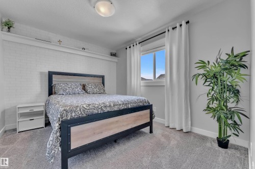 This room features a window with white curtains, a textured accent wall, and carpeting - 6406 169 Avenue, Edmonton, AB - Indoor Photo Showing Bedroom