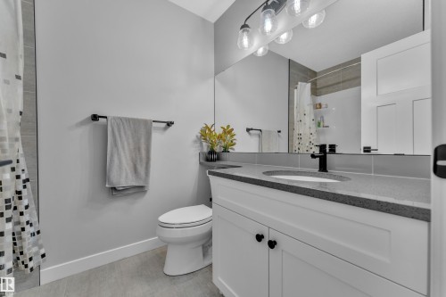 Modern bathroom featuring a double vanity with stone countertops, a large mirror, and a toilet - 6406 169 Avenue, Edmonton, AB - Indoor Photo Showing Bathroom