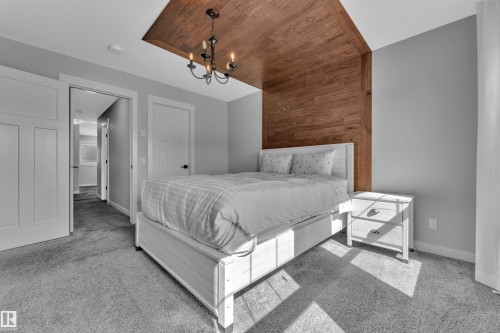 Bedroom featuring a distinctive wood panel accent wall and ceiling detail, complemented by a chandelier - 6406 169 Avenue, Edmonton, AB - Indoor Photo Showing Bedroom