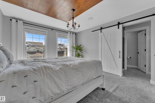 This room features a wood plank ceiling, a chandelier, and a barn door - 6406 169 Avenue, Edmonton, AB - Indoor Photo Showing Bedroom