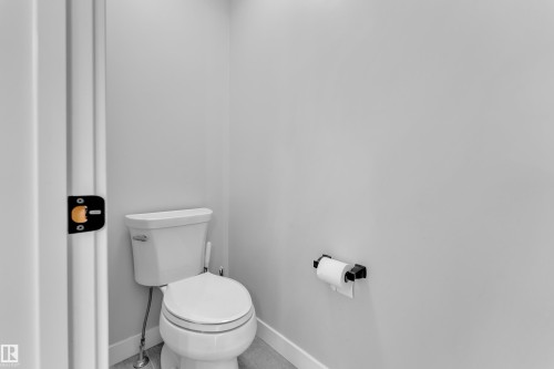 The powder room features a classic white toilet and a wall-mounted toilet paper holder - 6406 169 Avenue, Edmonton, AB - Indoor Photo Showing Bathroom