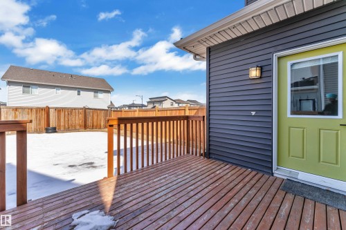 The property features a wooden deck with a railing, a dark grey siding exterior, and a lime green exterior door with a window - 6406 169 Avenue, Edmonton, AB - Outdoor With Exterior