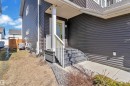 The property features dark horizontal siding, a light-colored front door, and a covered porch with white railings - 6406 169 Avenue, Edmonton, AB  - Outdoor With Exterior 
