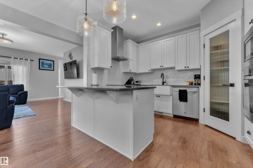 The kitchen features white cabinetry, a large kitchen island, hardwood flooring, and stainless steel appliances - 6406 169 Avenue, Edmonton, AB - Indoor Photo Showing Kitchen With Upgraded Kitchen