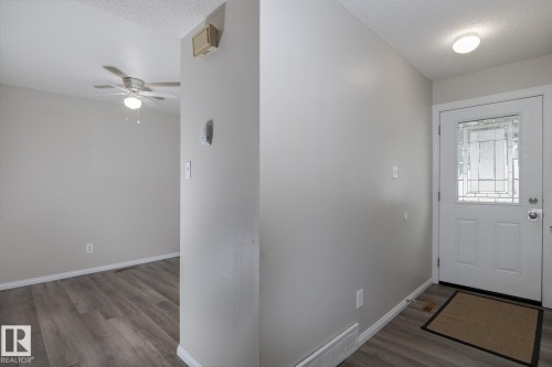Entryway featuring a white door with decorative glass inserts, a flush-mount ceiling light, and durable plank flooring - 37 Woodvale Village, Edmonton, AB - Indoor Photo Showing Other Room