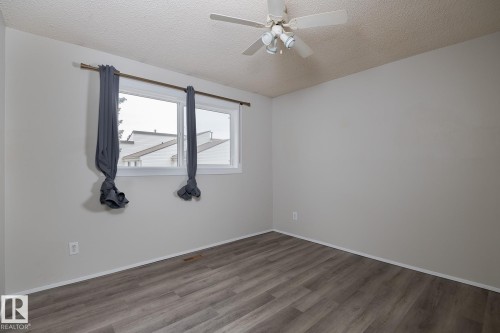 This room features a window providing natural light, a ceiling fan, and modern wood-style flooring - 37 Woodvale Village, Edmonton, AB - Indoor Photo Showing Other Room
