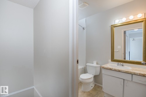 The bathroom features a vanity with a counter and an ornate framed mirror with overhead lighting - 37 Woodvale Village, Edmonton, AB - Indoor Photo Showing Bathroom