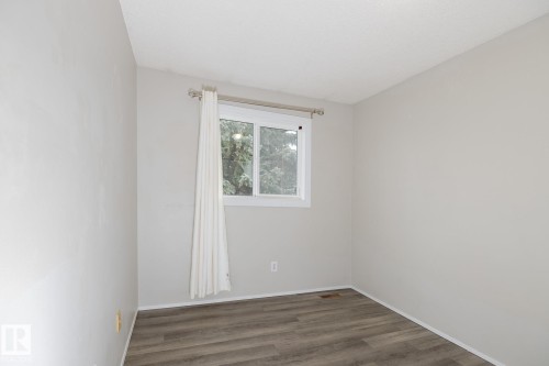 This room features neutral-toned walls, a window providing natural light, and wood-look flooring - 37 Woodvale Village, Edmonton, AB - Indoor Photo Showing Other Room