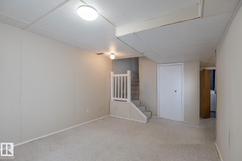 The finished area features light-colored carpeting and recessed lighting, with a staircase leading to an upper level - 37 Woodvale Village, Edmonton, AB - Indoor Photo Showing Other Room