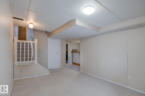 This finished space features light-colored carpeting, white paneled walls, and a drop ceiling with recessed lighting - 37 Woodvale Village, Edmonton, AB - Indoor Photo Showing Other Room