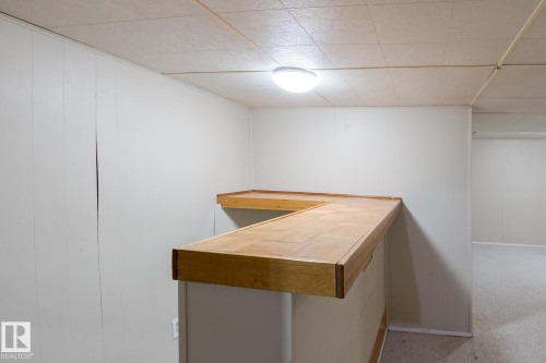 The property features a built-in bar area with a wooden countertop and a drop ceiling - 37 Woodvale Village, Edmonton, AB - Indoor Photo Showing Other Room