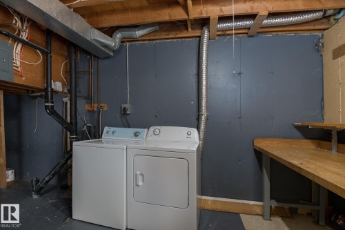 Dedicated laundry area with a washer and dryer, exposed ceiling joists, and a utility sink - 37 Woodvale Village, Edmonton, AB - Indoor Photo Showing Laundry Room